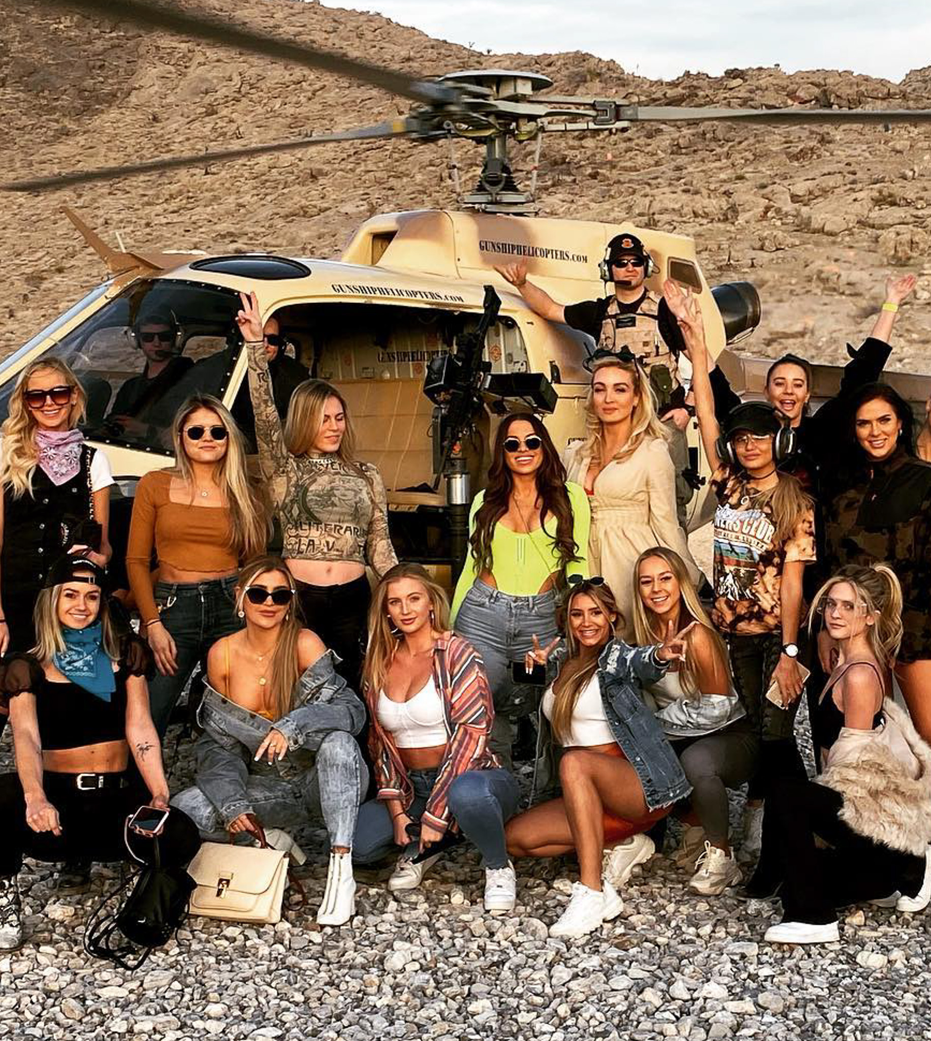 Group of women posing in front of a helicopter in desert